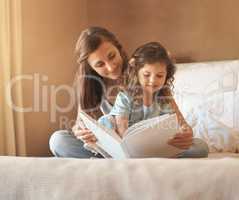 Once upon a time. a happy mother and daughter at home reading a storybook on the bed.