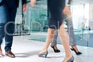 Always on the move. a group of unrecognizable businesspeople walking through the office.