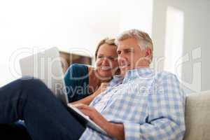 Browsing through the wide world online. a mature couple using a laptop together at home.