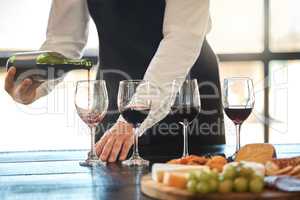 Luxury, fine dining and hospitality with a waiter pouring red wine at a restaurant. Preparing for a wine tasting with a professional sommelier, good service with quality drink by a male winemaker