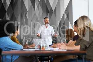 His presentations are always interesting and informative. a handsome mature businessman giving a presentation to his colleagues in the office.