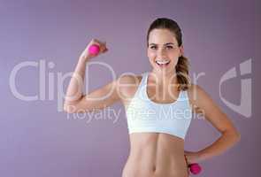 Lift weights then lose weight. Studio shot of a healthy young woman holding dumbbells posing against a purple background.