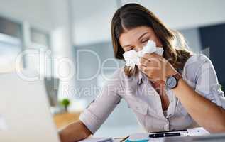 Having to blow my nose all the time is distracting. a businesswoman working in her office while suffering from allergies.