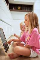 Listing the chores that need to be done. two little girls writing a list of chores on a chalkboard at home.