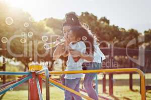 Bubbles make the world brighter. a mother and her daughter blowing bubbles at the park.