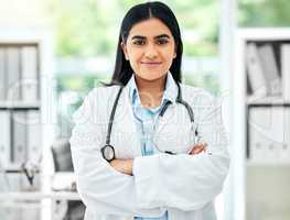 Portrait of a doctor working in her office with medical equipment at a modern surgery center. Happy healthcare worker standing with a stethoscope in hospital after a health and wellness consultation.