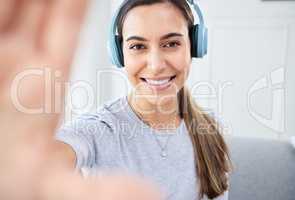 Portrait of happy woman take selfie and smile with headphones while listening to music in the living room. Young beautiful lady streaming a podcast at home and relax in lounge and express happiness