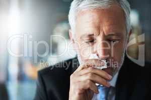 I hate being sick. a frustrated businessman using a tissue to sneeze in while being seated in the office.