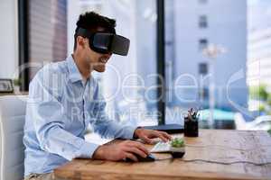 Immersed in a virtual world. a happy young businessman wearing a virtual reality headset while working at his desk in the office.