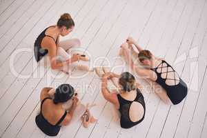 Ballet, fitness and stretching ballerina dancer group on floor, getting ready for rehearsal in dance studio. Above females bonding and relaxing, preparing before a classic, elegant performance