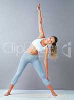 Reach for your goals. Full length portrait of an attractive and sporty young woman warming up against a grey background.