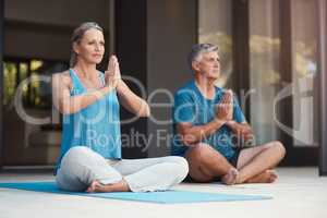 Let go of all stress and let peace take over. a mature couple peacefully engaging in a yoga pose with legs crossed and hands put together.