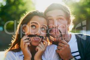 Were totally rocking these staches. a young couple enjoying a silly moment together while bonding outdoors.