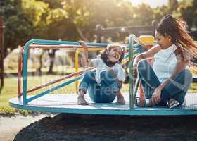 Enjoying some quality time out in the lovely sunshine. a mother and her daughter playing together on a merry-go-round at the park.