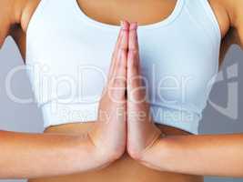 Yoga is exercise for the mind and body. an unrecognizable and sporty young woman doing yoga against a grey background.