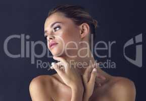 Her looks make time stand still. Studio shot of an attractive young woman posing while gently touching her neckline.