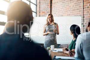 Bulletproofing her business before going on maternity leave. a pregnant businesswoman giving a presentation in the boardroom.