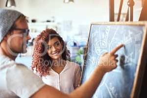 Shes quite impressed with his ideas. two businesspeople discussing their ideas on a blackboard.