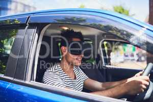 Technology adds another aspect to travel. a happy young man driving a car while wearing a virtual reality headset.