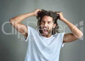 Hes boiled over with rage. Studio shot of a young man screaming against a grey background.