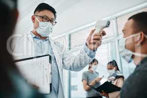 Doctor testing covid temperate in hospital appointment to prevent the spread of the virus. Healthcare compliance worker with health insurance document and face mask checking or scanning patient head