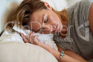 Sleep peacefully, wake happily. Close up shot of an attractive woman sleeping on her side in bed at home.