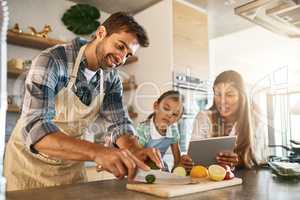 There are so many exciting recipes to try online. two happy parents and their young daughter trying a new recipe in the kitchen together.