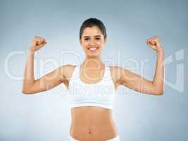 This is the body I worked hard for. Studio portrait of an attractive young woman flexing her muscles against a grey background.