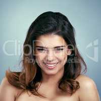 Joy is the best make up. Studio shot of a beautiful young woman smiling against a blue background.