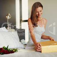 Something special for a special someone. a young woman opening a surprise gift at home.