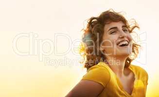 Yellow is the happiest color. a cheerful young woman laughing while standing outside at sunset.