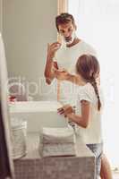 When can I start shaving, daddy. a happy little girl watching her father as her shaves by the sink.
