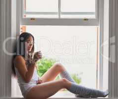 Hot and steamy, just how I like it. sexy young woman drinking coffee while sitting on a window ledge.