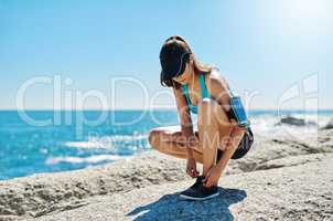This princess wears running shoes. a sporty young woman tying her shoelaces while out for a run.