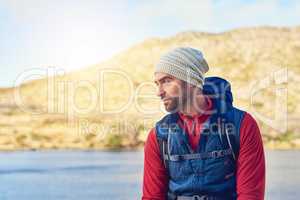 Fresh air helps him clear his mind. a thoughtful hiker admiring the view of a lake on a sunny day.