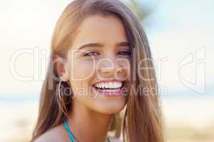 Her smile brightens up any day. Portrait of an attractive young woman standing outside on a sunny day.