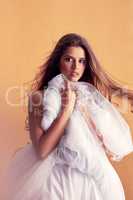 Shes a shy beauty. Portrait of a beautiful young woman covering herself with a ballet skirt in studio.