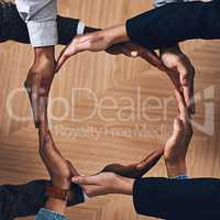 Coming together to unite as one. High angle shot of a group of unidentifiable businesspeople forming a circle with their hands.