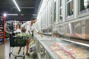 Through the produce aisle. Full length shot of a young mother doing grocery shopping with her kids.