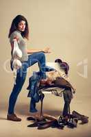 Even fashionistas have off days. Studio shot of a young woman choosing clothing piled on a chair against a brown background.