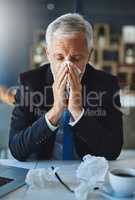I hope this doesnt get worse. a frustrated businessman using a tissue to sneeze in while being seated in the office.