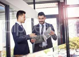 Let me pick your brain for a minute. two happy business partners discussing paperwork in the hallway in their office.