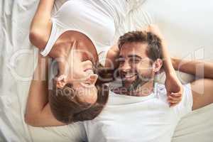 Only you give me that feeling. High angle shot of a happy young couple relaxing in bed together at home.