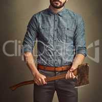 I know how to handle an axe and dress good. Studio shot of a young man posing with an axe against a green background.