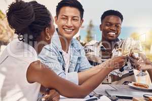 Diverse group toasting and celebrating friendship at an outdoor restaurant, having fun and laughing. Happy people cheers while bonding, talking and enjoying a celebration of good, exciting news