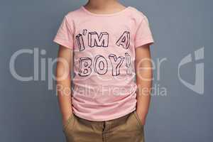 Fashion that makes a statement. Studio shot of a boy wearing a t shirt with Im a boy printed on it against a gray background.