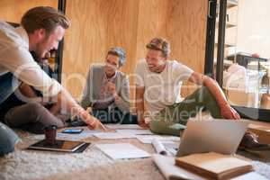 Working hard to make their latest project another success. a team of designers brainstorming on the floor in an office.