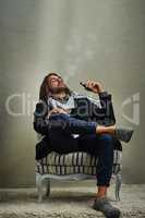 Smoking never looked this cool. a stylishly dressed man smoking an electronic cigarette while sitting in the studio.