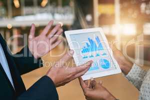 Looking at ways to keep their business growing. Closeup shot of two unrecognisable businesspeople analysing graphs on a digital tablet in an office.