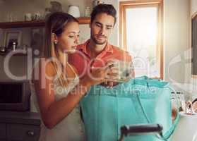Wrong order of grocery, food and kitchen products bought by a couple for home cook dinner or lunch. Unhappy male and female unpacking diet cooking supplies, ingredients or groceries from shopping bag